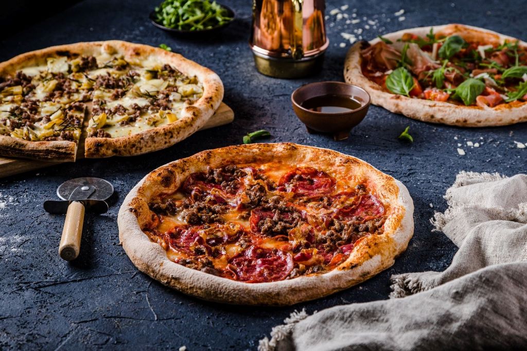 Fresh pizza dough balls rising in bowls, made with Vito's traditional Italian recipe