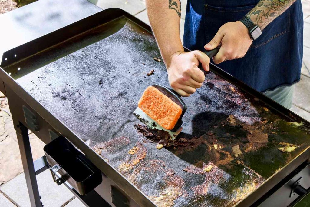 Person applying oil to a Blackstone griddle during the seasoning process