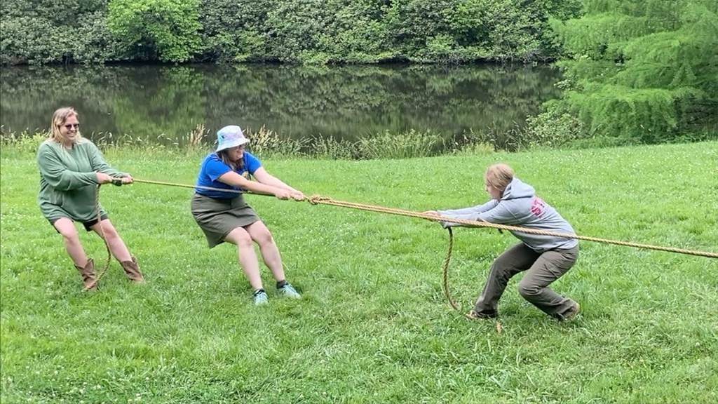 Hands pulling taut Faxco rope in outdoor tug-of-war, highlighting grip and strength against blurred green background for action-oriented durability.