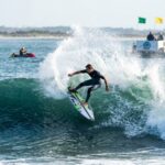 Professional surfers competing in offshore waves during a Charleston SC surfing tournament with support boats nearby