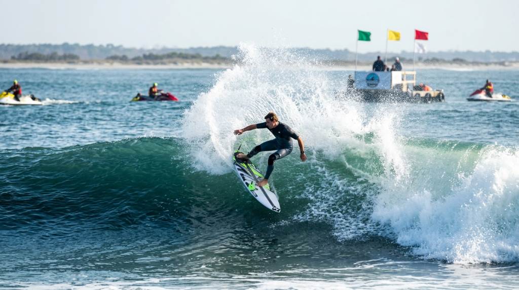 Professional surfers competing in offshore waves during a Charleston SC surfing tournament with support boats nearby
