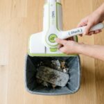 Hands pressing release button to drop dirty Shark VACMop pad.